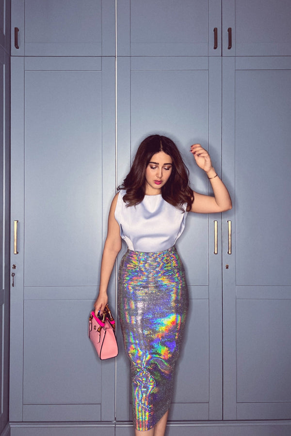 women in a shiny skirt holding a pink bag in front of blue lockers